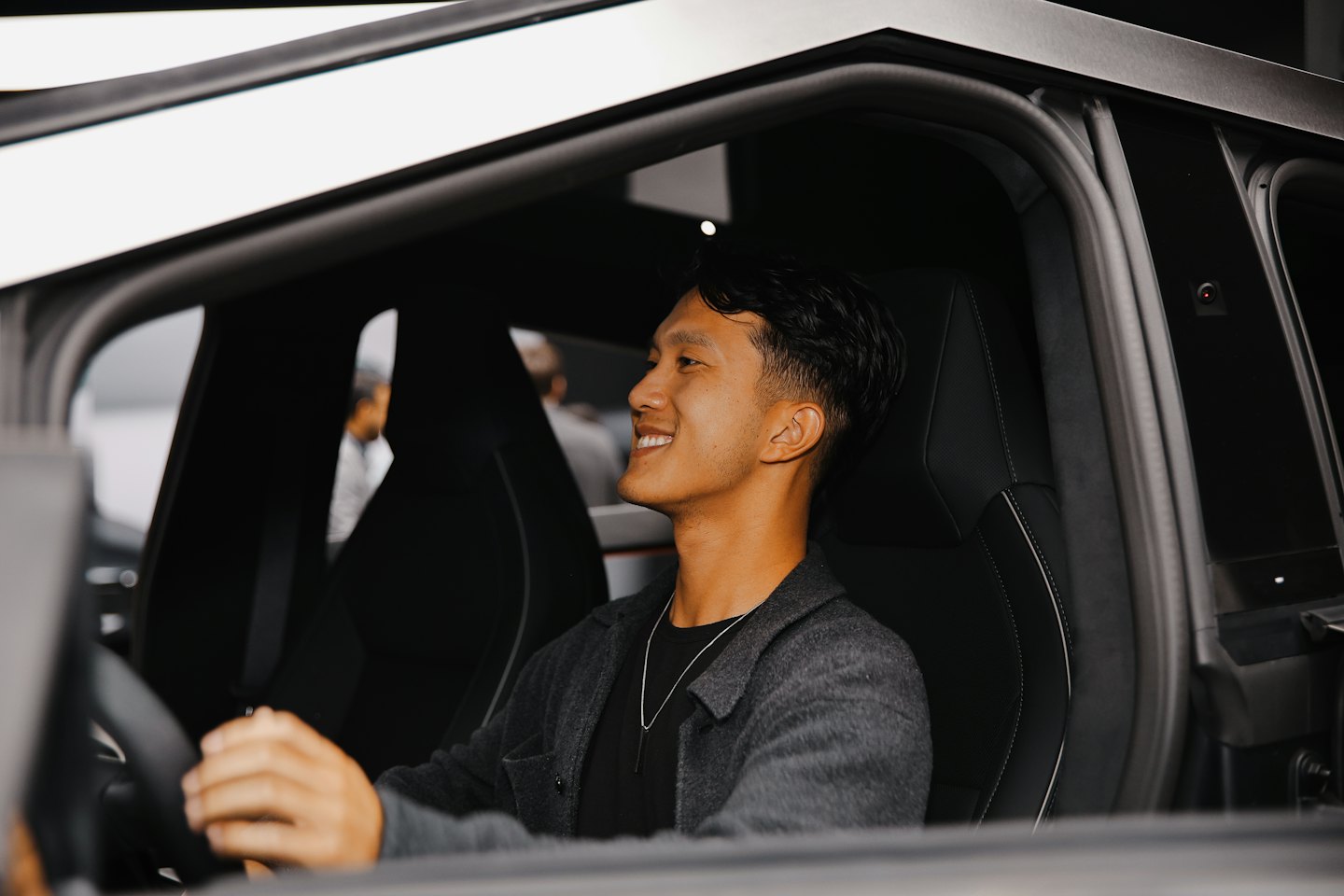 Man smiles while sitting in the driver seat of a car.