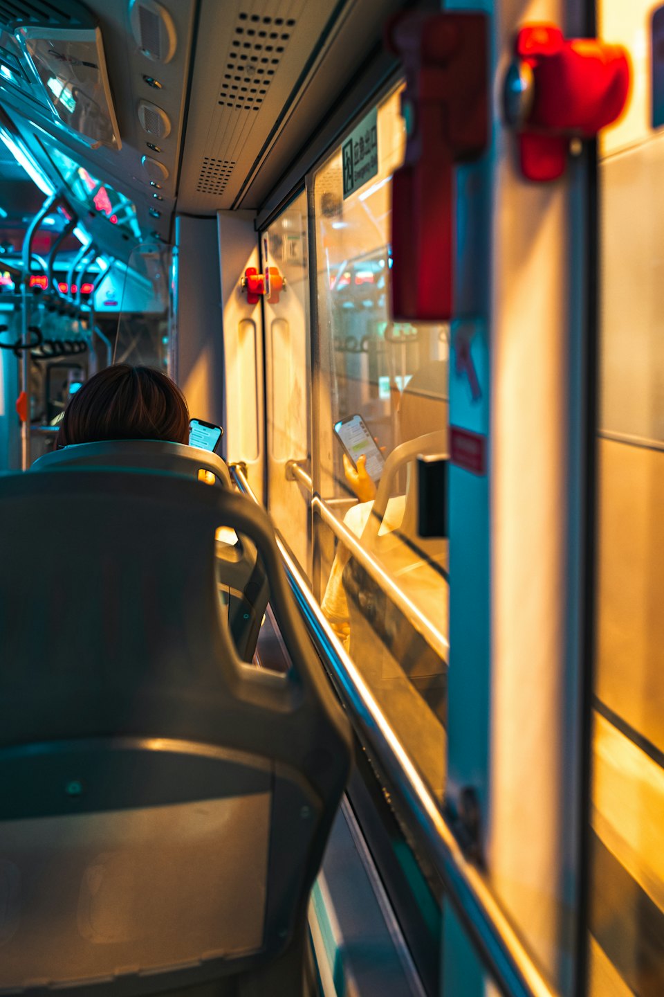 Person on bus looking at phone with city lights outside.